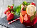Erfrischende alkoholfreie Bowle mit Erdbeeren, Zitrone und Minze, serviert in einem Glas mit Eiswürfeln.