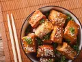Knusprig gebratene Tofuwürfel mit Sesam und Petersilie in einer Schüssel. So schmeckt Tofu köstlich!