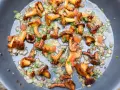 Pfifferlinge rezept: Goldgelbe Pfifferlinge braten mit Zwiebeln und Petersilie in einer Pfanne. Ein köstliches Gericht!