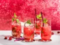 Vier erfrischende Bacardi Razz Mojitos mit Himbeeren und Minze, bereit zum Genießen.