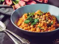 Herzhaftes Gericht mit Kichererbsen und Petersilie, verfeinert mit Garam Masala. Daneben liegen Gabel und Löffel.
