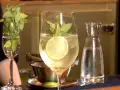 Erfrischender Hugo mit Limette und Minze, perfekt für ein Hugo Rezept. Daneben ein Glas mit Minze und eine Karaffe Wasser.