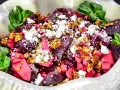 Rote Bete Salat mit Apfel, Feta und Walnüssen, garniert mit grünen Blättern. Ein farbenfroher und gesunder Genuss.