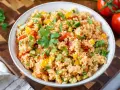 Frischer Couscous Salat mit Tomaten, Paprika und Petersilie, garniert mit einem Petersilienblatt.