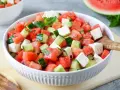 Erfrischender Wassermelone Feta Salat mit Gurke und Minze in einer weißen Schüssel, bereit zum Servieren.