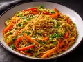 Ein Teller mit gebratenen Asia Noodles, garniert mit Erbsen, Paprika und Sesam. Ein köstliches Rezept für gebratene Asia Noodles.