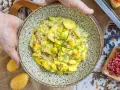 Ein Teller mit herzhaftem Kartoffelsalat mit Speck und frischen Kräutern, bereit zum Servieren.