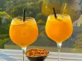 Zwei Gläser erfrischendes Aqua de Valencia mit Orangenscheiben und Eis, daneben eine Schale Nüsse.