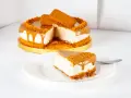 Ein Stück cremiger Lotus Cheesecake ohne Backen, mit Karamellglasiert und Keksbröseln bestreut.