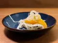 Ein erfrischender Fenchel-Orangen-Salat, garniert mit Pfeffer, in einer blauen Schale auf einem Holztisch.