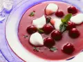 Erfrischende Kirschsuppe mit Sago, garniert mit Kirschen, Minze und weißen Tupfern.