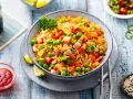 Schüssel mit Nasi Goreng: gebratener Reis mit Hühnchen, Erbsen, Karotten, Chili und Limettenspalten.