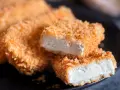 Knusprig gebratenes Tofu auf einem Teller. Die goldbraune Panade umhüllt das weiche Innere. Perfekt, um Tofu knusprig braten zu lernen.