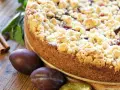 Ein saftiger Zwetschgenkuchen mit knusprigen Streuseln, daneben frische Zwetschgen und Zimtstangen. Perfekt für ein Streusel Rezept einfach!