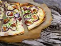 Flammkuchen mit klassischem Belag: Speck, Zwiebeln und Schnittlauch auf knusprigem Teig.