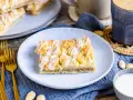 Ein Stück Prasselkuchen, wie aus einem DDR-Rezept, mit Zuckerguss und Streuseln. Dazu Kaffee und Mandeln.