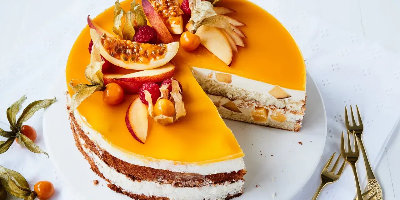 Eine köstliche Pfirsich Maracuja Torte mit frischen Früchten und Sahne. Ein Stück ist bereits angeschnitten.