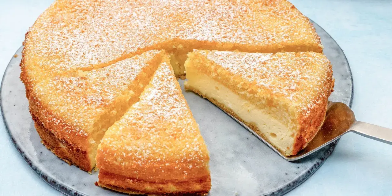 Ein saftiger Käsekuchen, bestäubt mit Puderzucker. Ein Stück wird gerade mit einem Tortenheber herausgehoben. Dreh dich um, Kuchen, du siehst köstlich aus!