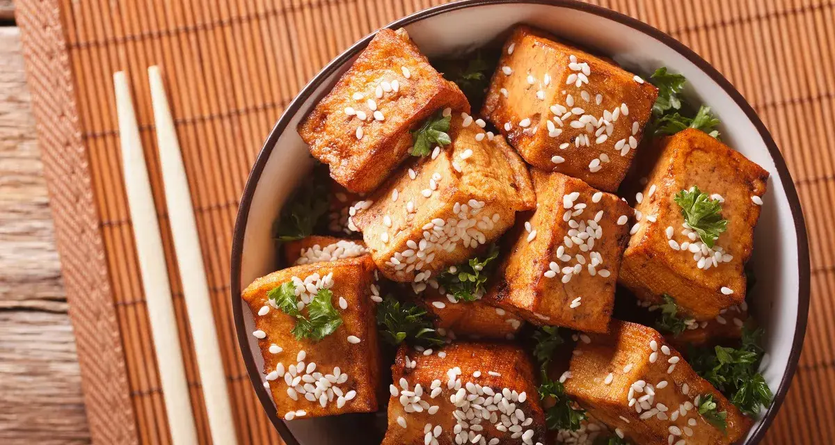 Knusprig gebratene Tofuwürfel mit Sesam und Petersilie in einer Schüssel. So schmeckt Tofu köstlich!