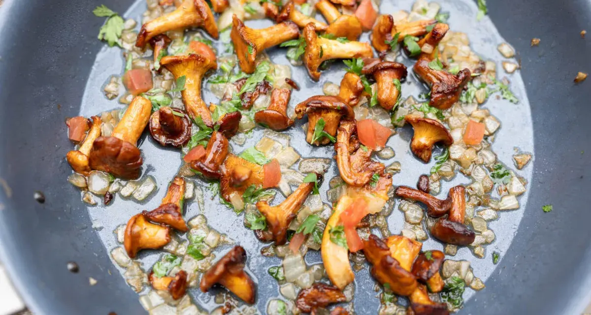 Pfifferlinge rezept: Goldgelbe Pfifferlinge braten mit Zwiebeln und Petersilie in einer Pfanne. Ein köstliches Gericht!