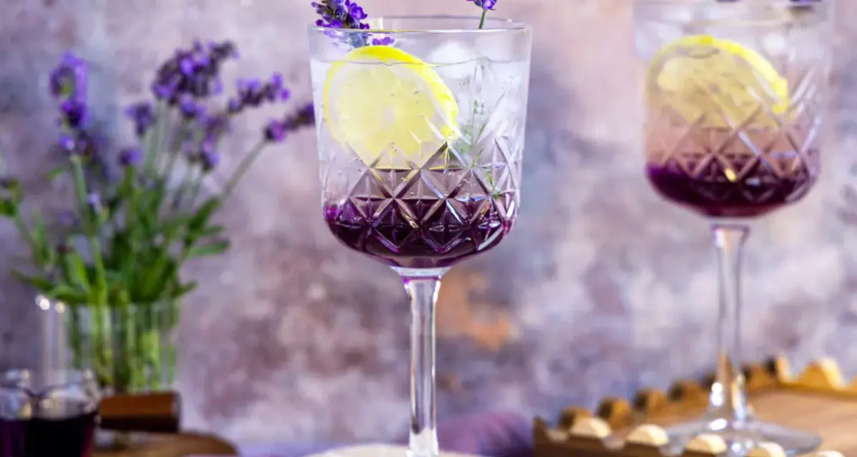 Erfrischender Lavendel Spritz mit Zitrone und Eis in eleganten Gläsern, garniert mit Lavendelblüten.