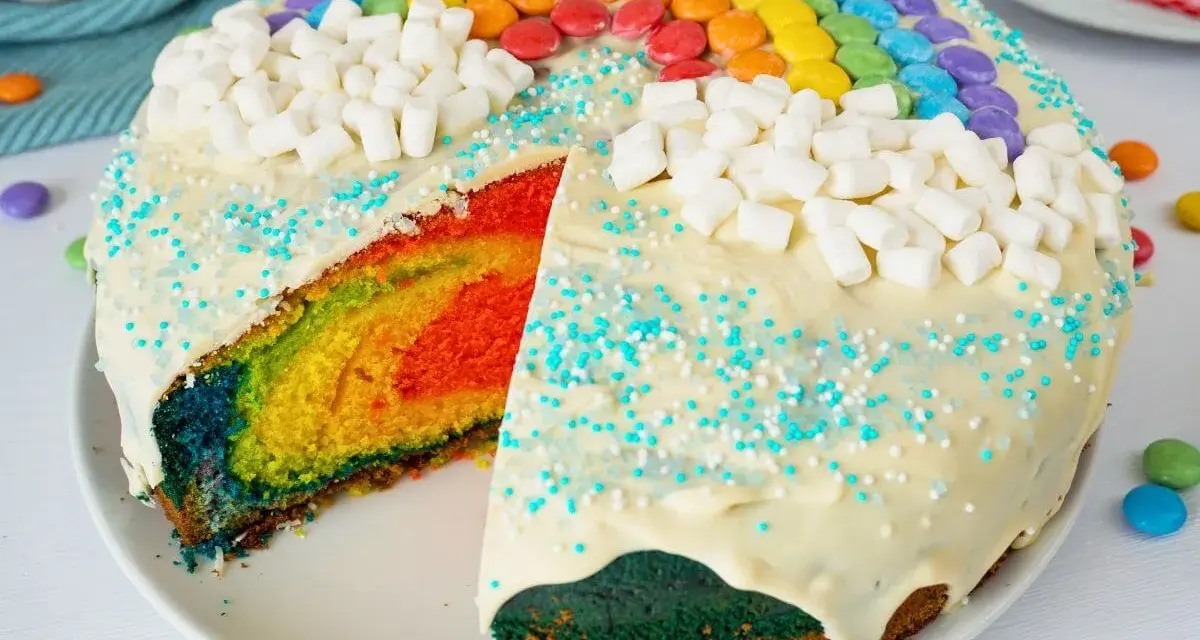 Bunter, sommerlicher Kuchen mit Regenbogen-Schichten, weißen Marshmallows und bunten Smarties.