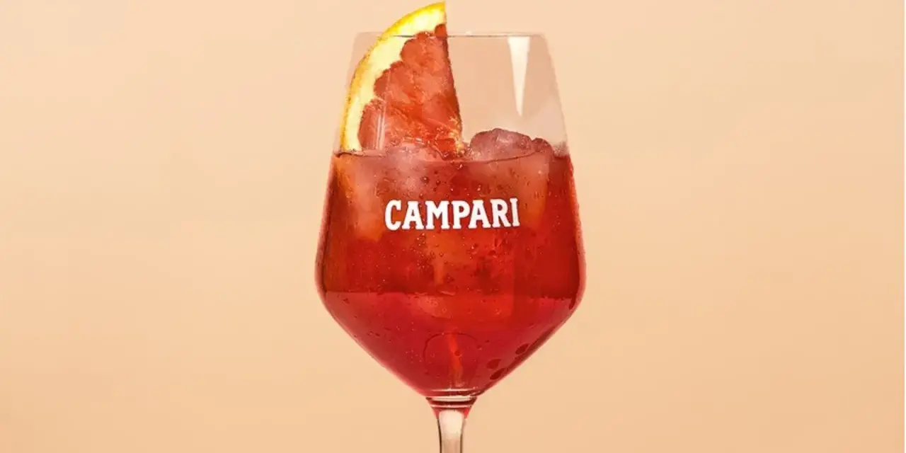 Ein Glas Campari mit Eis und einer Orangenscheibe. Entdecke die Vielfalt der Aperol Spritz Varianten!