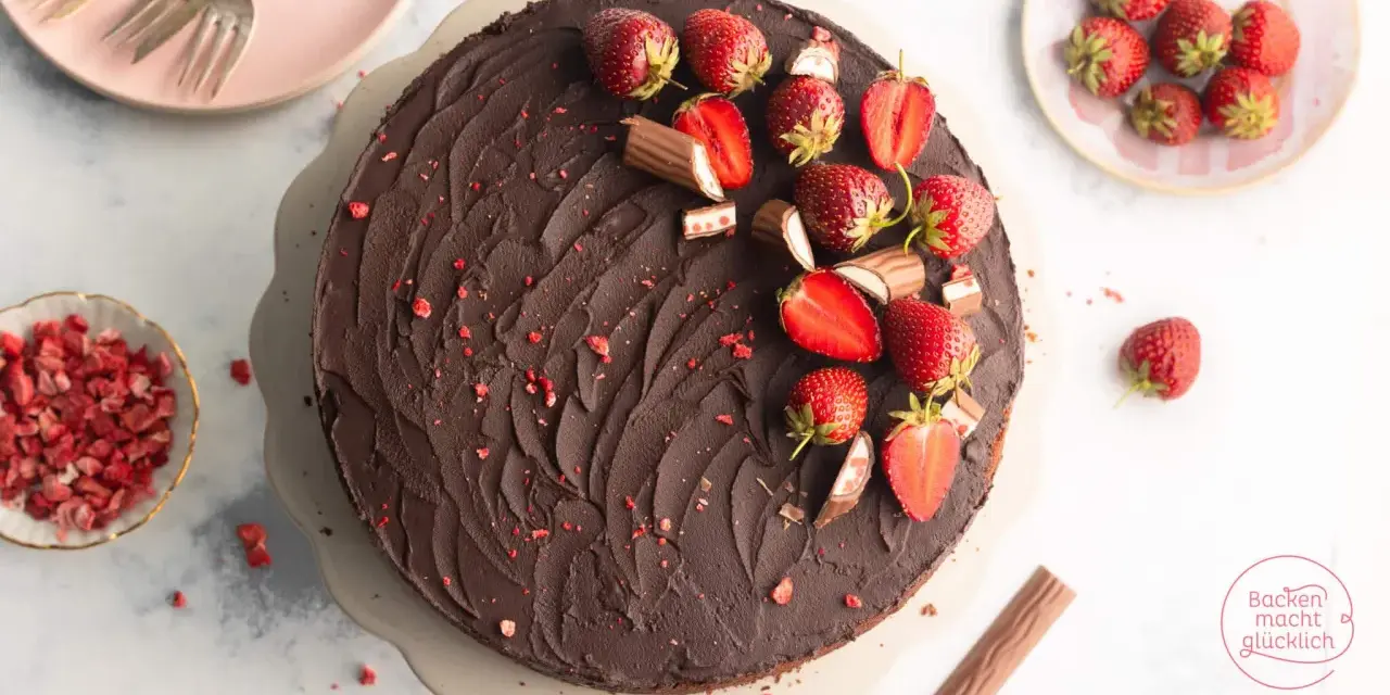 Eine köstliche Erdbeer Yogurette Torte mit Schokoladenglasur, frischen Erdbeeren und kleinen Schokostückchen.
