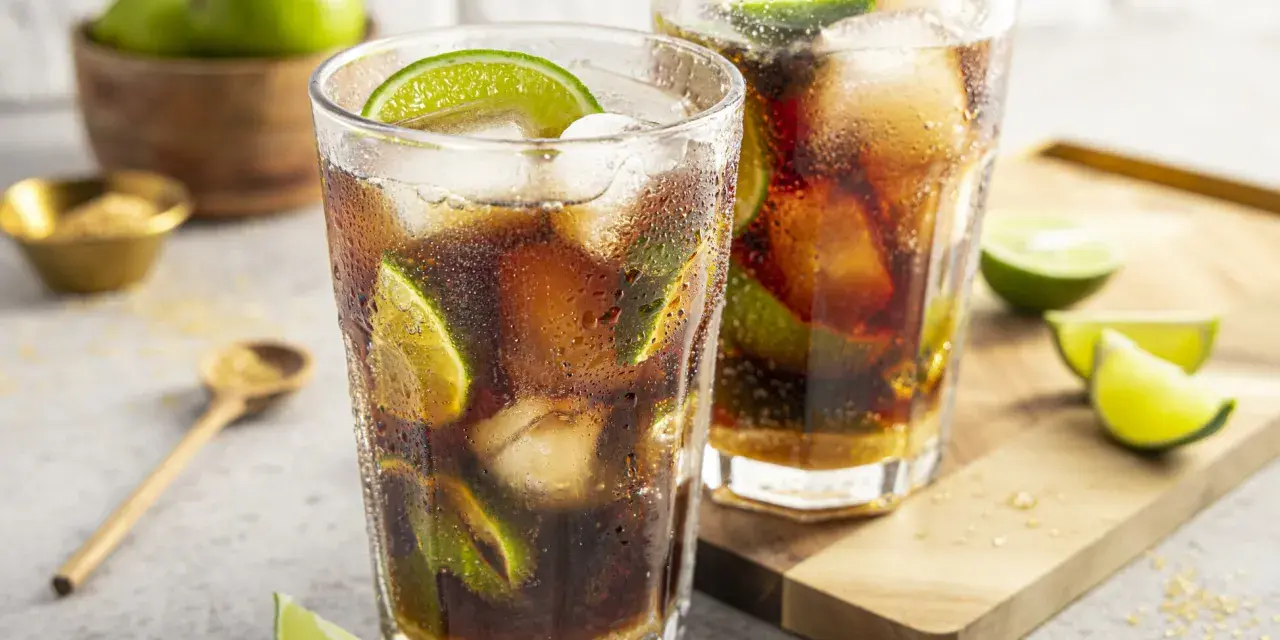 Zwei erfrischende Cuba Libre mit Eis und Limettenspalten, bereit zum Genuss.