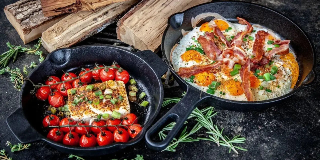 Zwei Gusseisenpfannen mit Eiern, Speck und Kirschtomaten mit Feta – perfekt für low carb grillen.