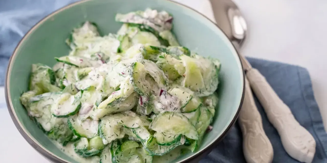Frischer gurkensalat mit saurer sahne, Dill und roten Zwiebeln in einer Schüssel, bereit zum Servieren.