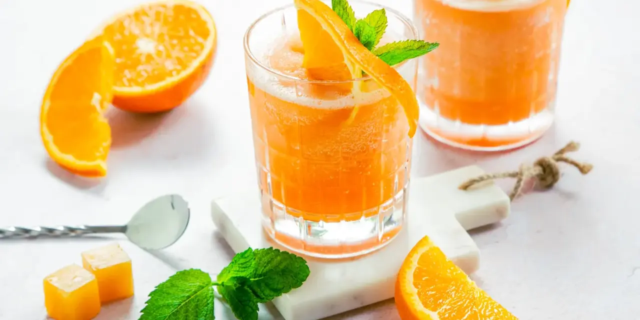 Erfrischender Aperol mit Orangensaft, garniert mit frischer Minze und Orangenspalten. Perfekt für einen sonnigen Nachmittag.