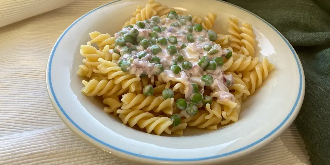 Fusilli-Pasta mit einer cremigen Sauce aus Erbsen und Speck, ein klassisches italienisches Gericht.