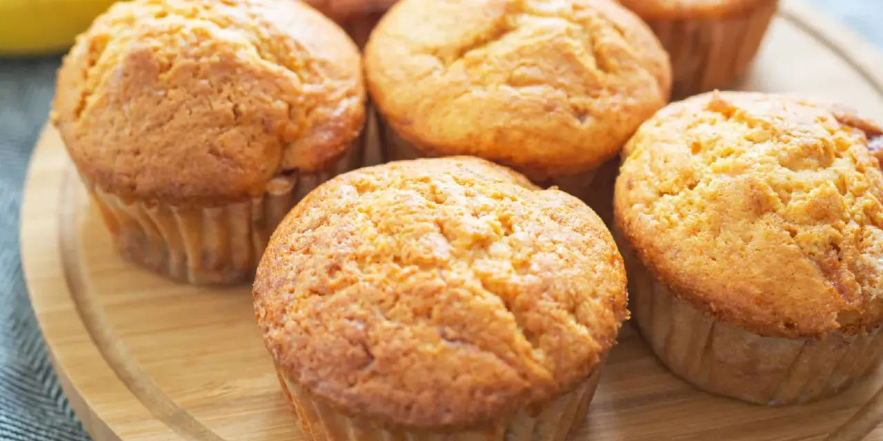Goldbraune Bananen Quark Muffins auf einem Holzbrett, bereit zum Genießen.