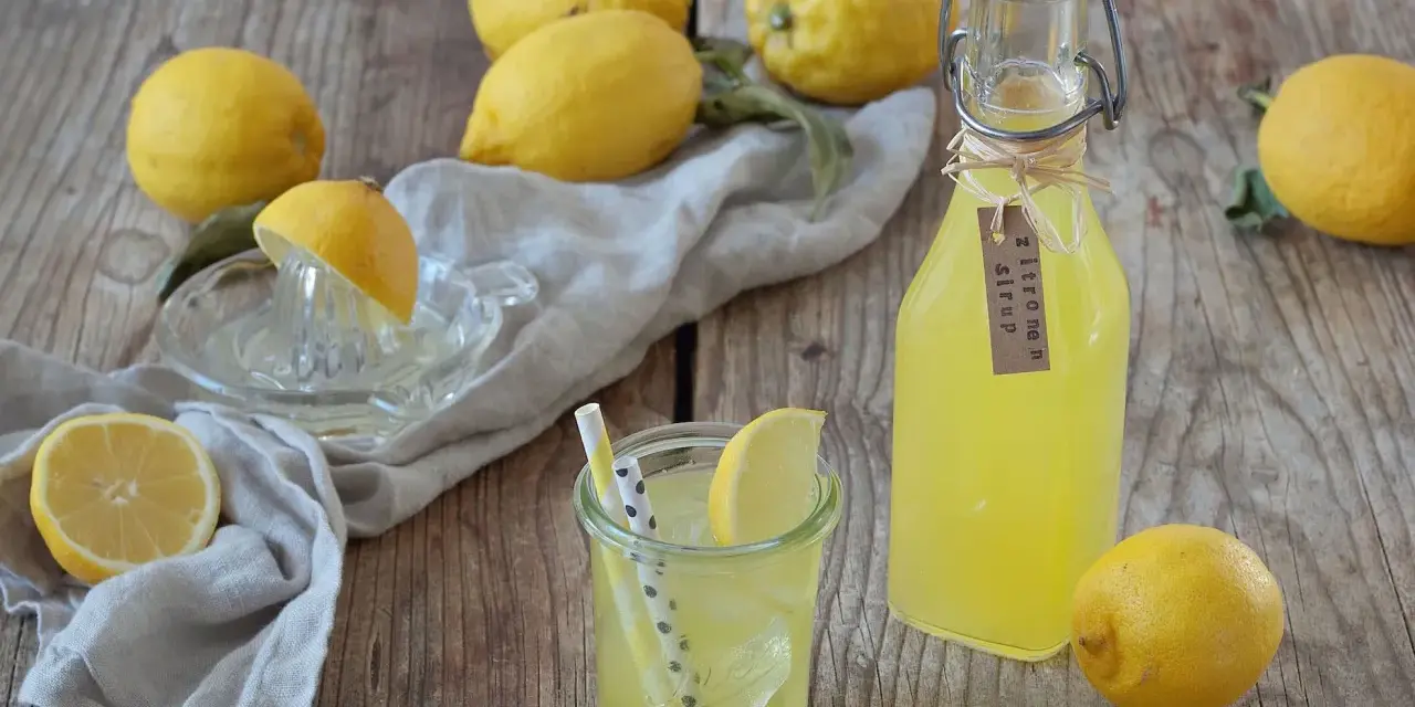 Frische Zitronen und selbstgemachter Zitronensirup in einer Flasche, bereit zum Genießen.