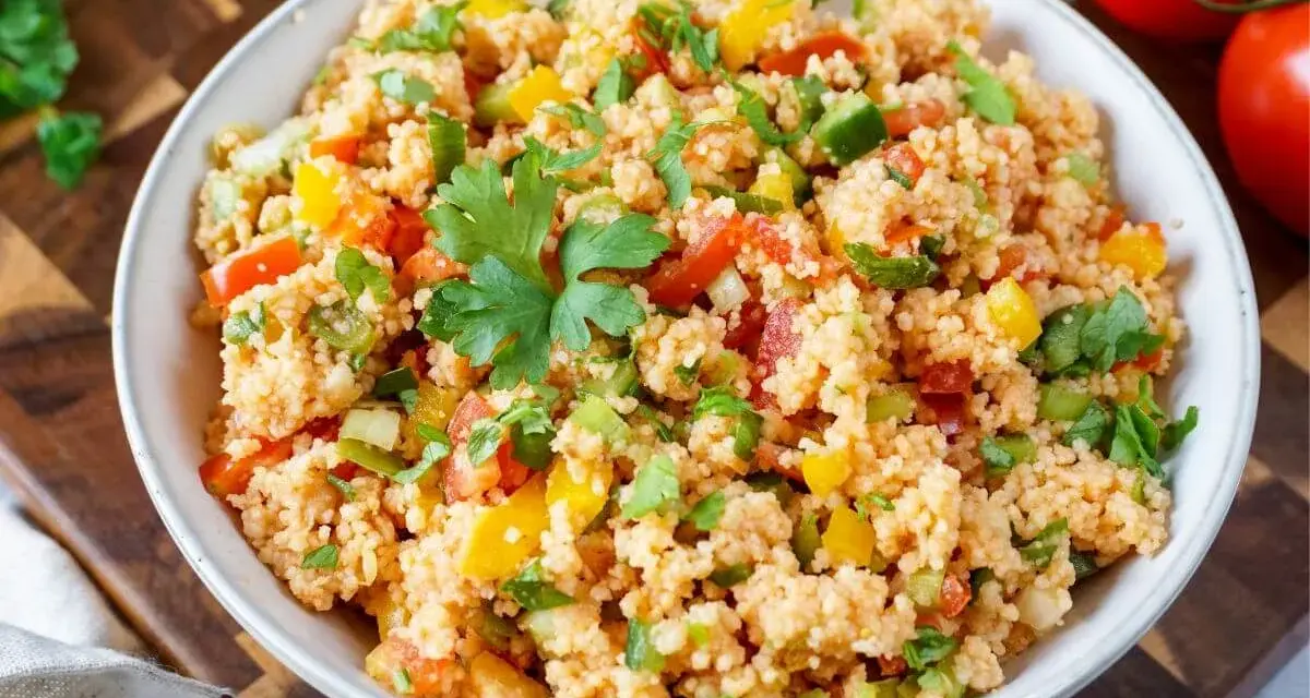 Frischer Couscous Salat mit Tomaten, Paprika und Petersilie, garniert mit einem Petersilienblatt.