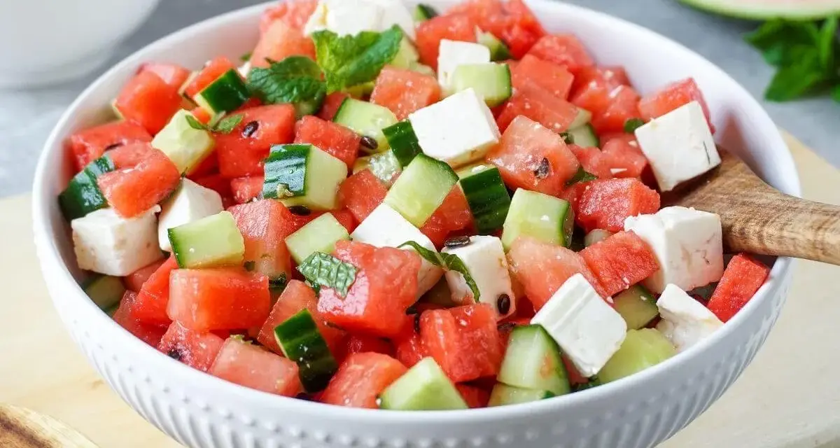 Erfrischender Wassermelone Feta Salat mit Gurke und Minze in einer weißen Schüssel, bereit zum Servieren.