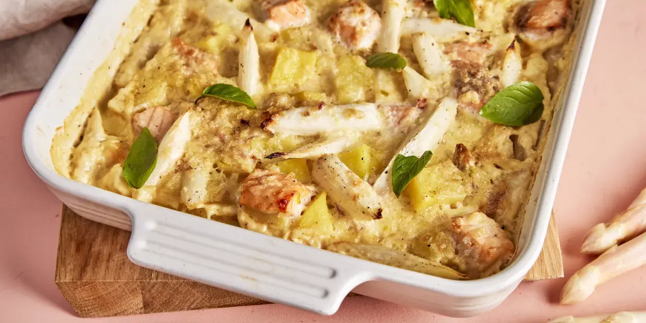 Ein köstlicher Spargel Lachs Auflauf in einer weißen Auflaufform, garniert mit Basilikum. Dazu frischer Spargel.