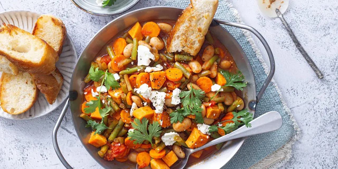 Herzhaftes Gericht mit Bohnen, Karotten und Süßkartoffeln, perfekt für Camping-Rezepte mit wenig Zutaten. Mit Feta und Brot serviert.