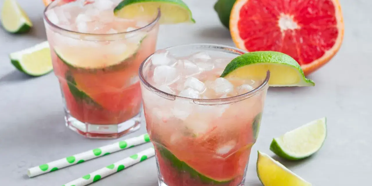 Erfrischender Aperol Paloma mit Grapefruit und Limette, garniert mit frischen Fruchtstücken und Eis.