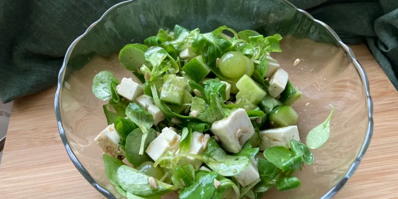 Erfrischender Salat mit grünen Weintrauben, Feta und Gurke in einer Glasschüssel.