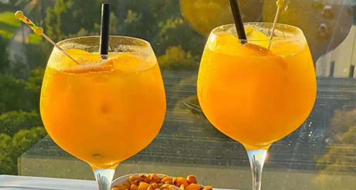 Zwei Gläser erfrischendes Aqua de Valencia mit Orangenscheiben und Eis, daneben eine Schale Nüsse.