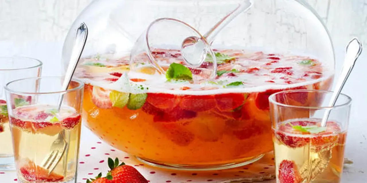 Erfrischendes Bowle-Rezept mit Erdbeeren und Minze in einer großen Glasbowle, bereit zum Servieren in Gläsern.