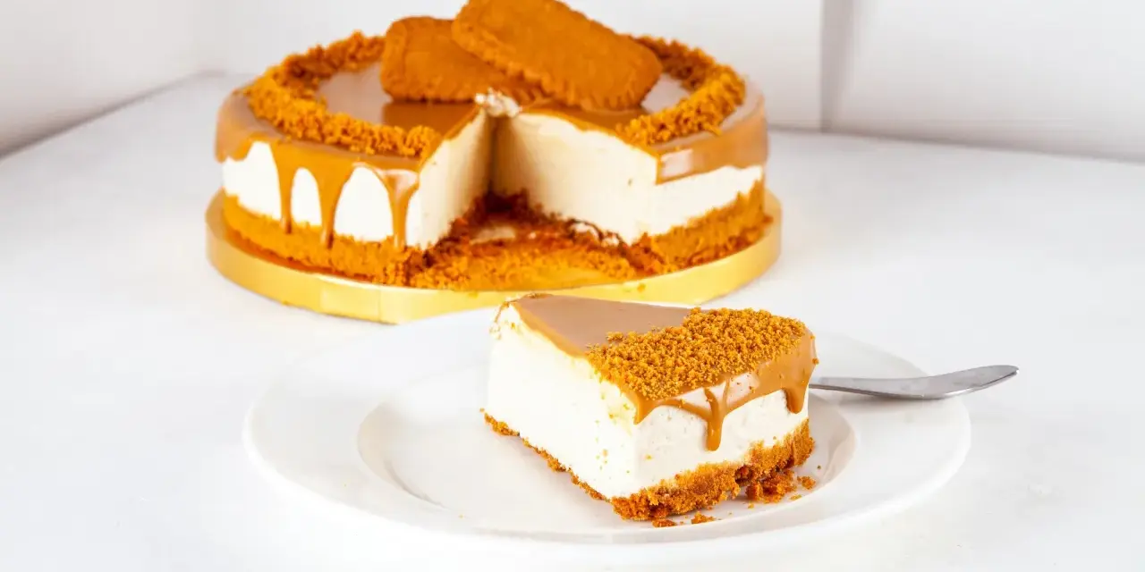 Ein Stück cremiger Lotus Cheesecake ohne Backen, mit Karamellglasiert und Keksbröseln bestreut.