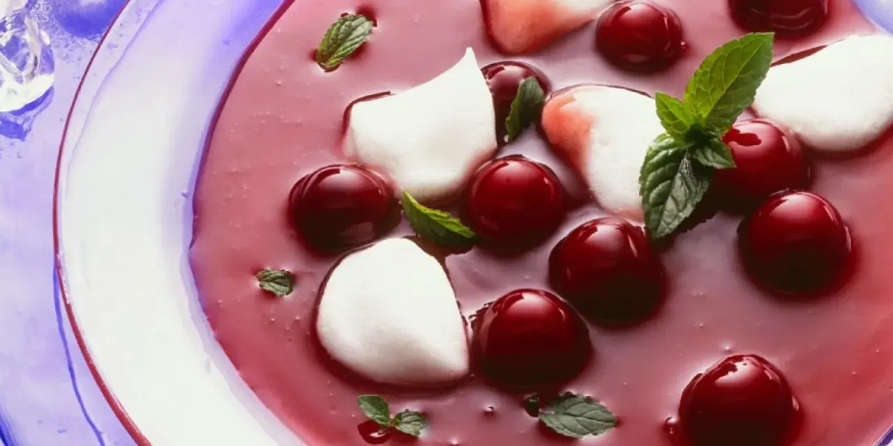 Erfrischende Kirschsuppe mit Sago, garniert mit Kirschen, Minze und weißen Tupfern.