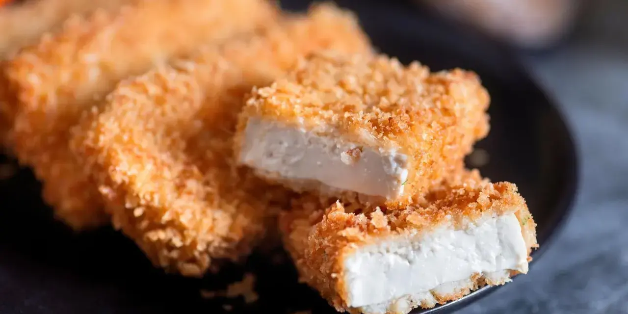Knusprig gebratenes Tofu auf einem Teller. Die goldbraune Panade umhüllt das weiche Innere. Perfekt, um Tofu knusprig braten zu lernen.