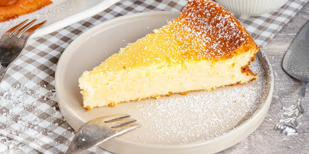 Ein saftiges Stück Kokoskuchen mit Pudding, gebacken in einer Springform, bestäubt mit Puderzucker.