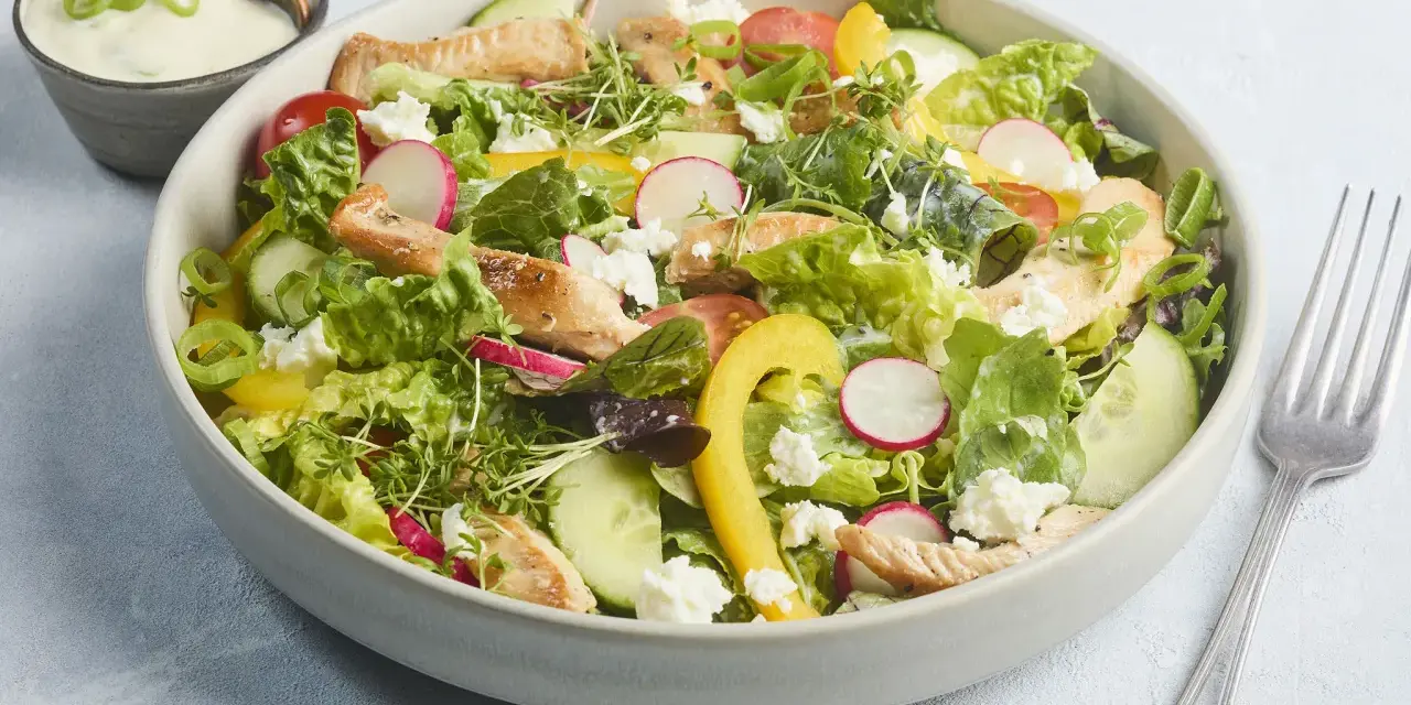 Frischer Salat mit Putenstreifen, Gurken, Radieschen, Tomaten, gelber Paprika und Feta. Dazu ein cremiges Dressing.