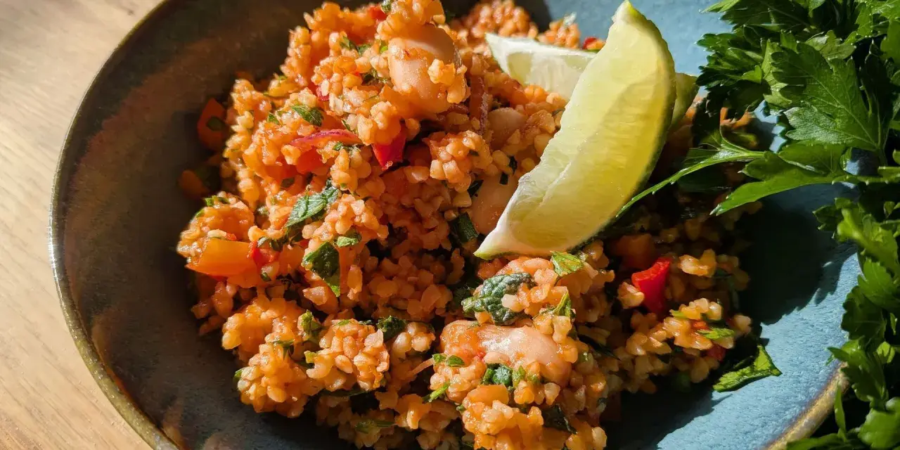 Ein erfrischender bulgursalat mit minze, garniert mit Limettenspalten und frischer Petersilie.