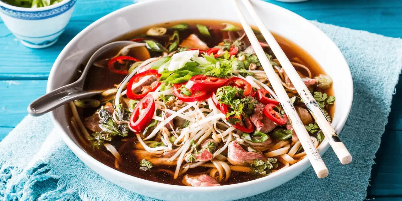 Eine Schüssel dampfendes Pho mit Rindfleisch, Nudeln, Sprossen und Chili. Was ist Pho? Ein aromatisches vietnamesisches Gericht.